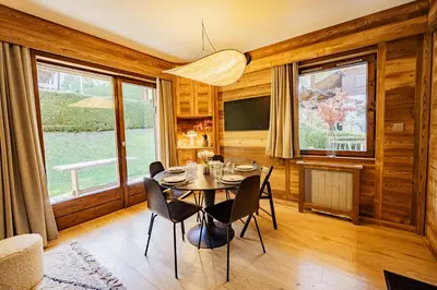 a dining room with a table and chairs and windows at Le Majestic - Proche pistes et centre ville in Megève
