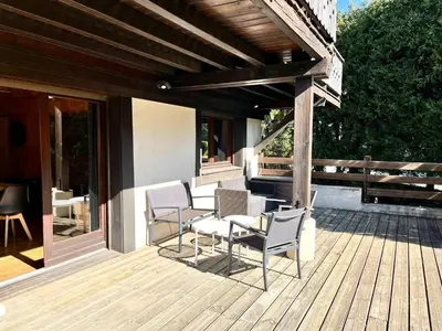 a deck with chairs and tables on a house at Cozy apartment chalet atmosphere in Megève