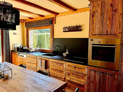 a kitchen with wooden cabinets and a wooden table at Cozy apartment chalet atmosphere in Megève