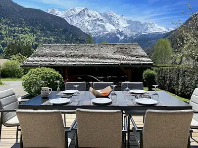 a table and chairs on a patio with mountains at Alpen Lounge in Servoz