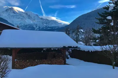 a cabin covered in snow with mountains in the background at Alpen Lounge in Servoz