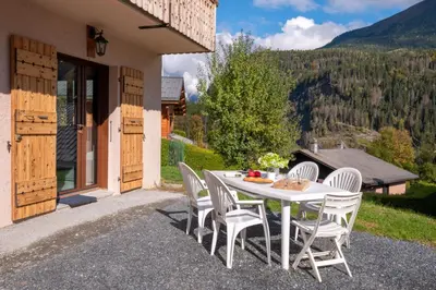 a table and chairs on a patio with a view at Apartment at the foot of the slopes with view in Les Houches