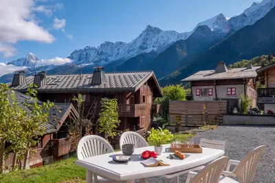 a table and chairs with mountains in the background at Apartment at the foot of the slopes with view in Les Houches
