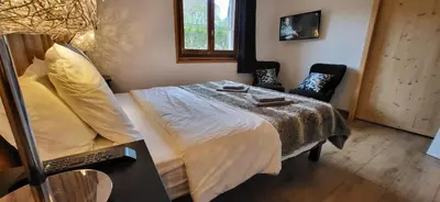 a bedroom with a bed and a chair and a window at Chalet Mugnier in Samoëns
