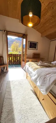 a bedroom with a bed and a large window at Chalet Mugnier in Samoëns