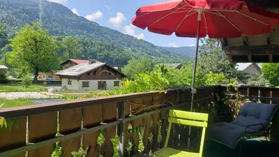 a balcony with two chairs and an umbrella at Chalet Mugnier in Samoëns