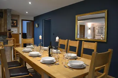 a long wooden table with chairs and a mirror at Chalet Mugnier in Samoëns