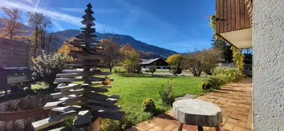 a garden with a wooden christmas tree and a stump at Chalet Mugnier in Samoëns