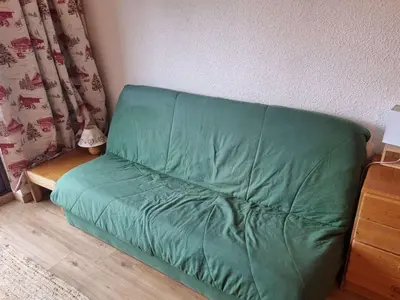 a green couch sitting in a corner of a room at Studio cosy 4 pers, 300m des pistes, Flaine - FR-1-687-97 in Arâches-la-Frasse