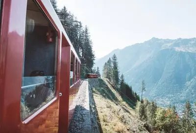 a red train traveling down a hill with a view at Argy - Apart Moderne - Vue MtBlanc - 5mn Pistes - Parking in Chamonix-Mont-Blanc