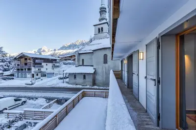 a church with snow on the ground next to a building at Wim in Les Houches