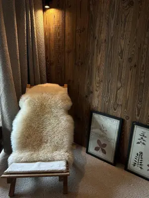 a white furry chair in a room with two pictures at Cocon de charme à Megève, confort et vue in Megève