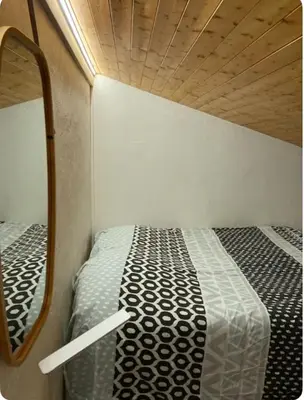 a small room with a bed and a mirror at 2 bedroom apartment, in Saint-Gervais-les-Bains