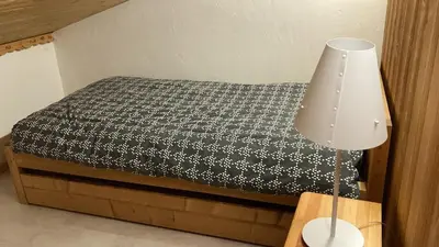 a bed with a black and white bedspread and a lamp at 2 bedroom apartment, in Saint-Gervais-les-Bains