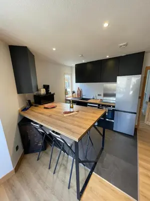 a kitchen with a wooden table and a refrigerator at BlackWood Lodge in Saint-Gervais-les-Bains