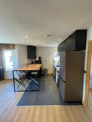 a kitchen with a table and a refrigerator at BlackWood Lodge in Saint-Gervais-les-Bains