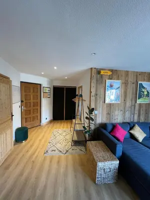 a living room with a blue couch and a wooden floor at BlackWood Lodge in Saint-Gervais-les-Bains