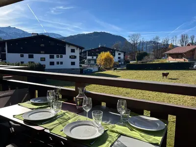 a table with glasses and plates on a balcony with a view at Sunny 2 Bedrooms Apartment for 4 in Megève Jaillet, right on the Ski Slopes in Megève