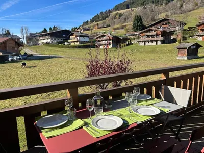a table with plates and wine glasses on a balcony at Sunny 2 Bedrooms Apartment for 4 in Megève Jaillet, right on the Ski Slopes in Megève