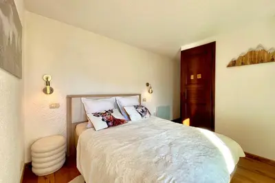 a bedroom with a large bed with white sheets and pillows at Joly Story in Megève