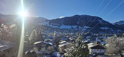 a view of a town in the mountains with the sun at Joly Story in Megève