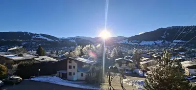 a view of a village in the snow with the sun at Joly Story in Megève