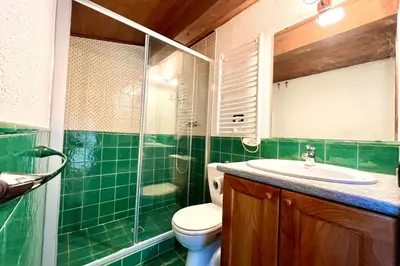 a green tiled bathroom with a toilet and a sink at Joly Story in Megève