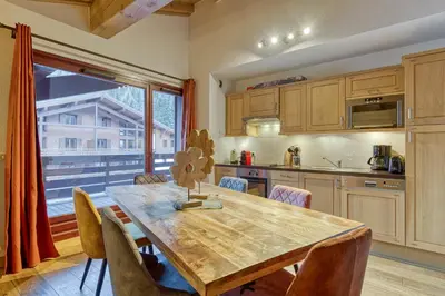 a kitchen with a wooden table and a large window at Appartement LE BUET skis aux pieds, piscine & Spa in Vallorcine