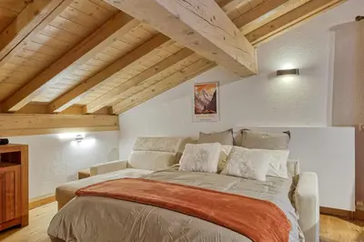 a large bed in a room with wooden ceilings at Appartement LE BUET skis aux pieds, piscine & Spa in Vallorcine