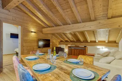 a dining room with a wooden table and chairs at Appartement LE BUET skis aux pieds, piscine & Spa in Vallorcine