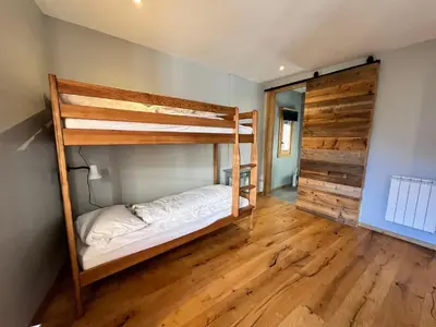 a bedroom with two bunk beds and a wooden floor at Chalet rénové à Samoëns, proche centre, skis-bus - FR-1-624-186 in Samoëns