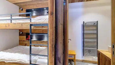 a bedroom with bunk beds and a chair at Appartement Haut de gamme- Rochebrune aux pieds des pistes- 3 chambres in Megève