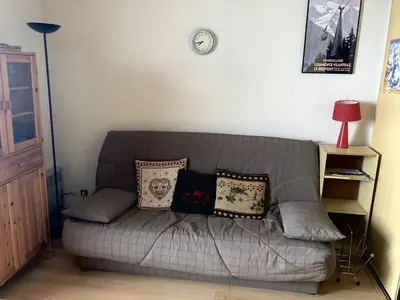 a couch in a living room with a clock on the wall at Studio 4 pers avec balcon au pied des pistes - FR-1-687-117 in Arâches-la-Frasse