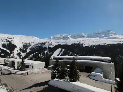 a building with a snow covered mountain in the background at Studio 4 pers avec balcon au pied des pistes - FR-1-687-117 in Arâches-la-Frasse