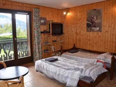 a bedroom with a bed and a table and a balcony at Charmant 2 pièces avec WIFI et 4 couchages à Le Pernant - FR-1-836-16 in Arâches-la-Frasse