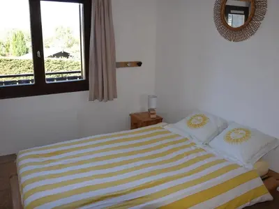 a bedroom with a bed with a yellow and white striped blanket at Charmant 2 pièces avec WIFI et 4 couchages à Le Pernant - FR-1-836-16 in Arâches-la-Frasse