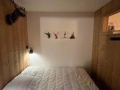 a bedroom with a bed and a wall with some pictures at Appartement rénové 2 pièces, centre station, garage, animaux admis - FR-1-836-24 in Arâches-la-Frasse
