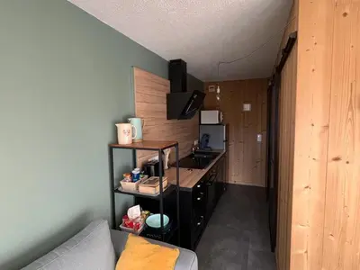 a living room with a couch and a kitchen at Appartement rénové 2 pièces, centre station, garage, animaux admis - FR-1-836-24 in Arâches-la-Frasse