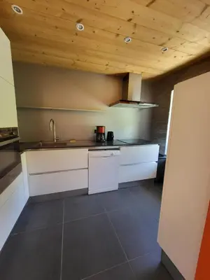 a kitchen with white cabinets and a wooden ceiling at La Sapone et Grange de Bovère in Sixt