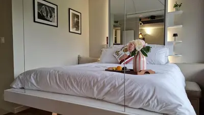 a bedroom with a white bed with a vase of flowers at Cristaux Studio, with view to Mont Blanc in Combloux