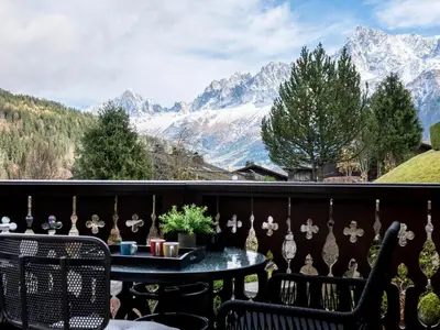 a balcony with a table and chairs and mountains at Refuge d'Ian - Close to Ski Piste Prarion - Swimming pool & Gym - By Cozee Rentals in Les Houches
