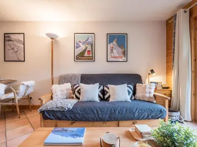 a living room with a blue couch and pictures on the wall at Refuge d'Ian - Close to Ski Piste Prarion - Swimming pool & Gym - By Cozee Rentals in Les Houches