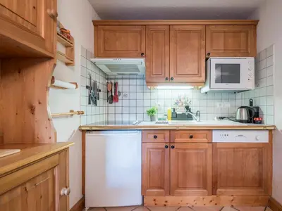 a kitchen with wooden cabinets and a white dishwasher at Refuge d'Ian - Close to Ski Piste Prarion - Swimming pool & Gym - By Cozee Rentals in Les Houches