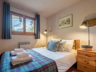 a bedroom with a bed with two pillows and a window at Refuge d'Ian - Close to Ski Piste Prarion - Swimming pool & Gym - By Cozee Rentals in Les Houches