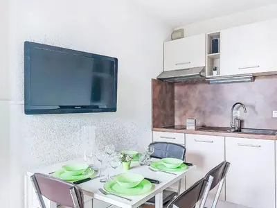 a kitchen with a table with chairs and a tv at Studio L'aiguille noire by Interhome in Bionnay