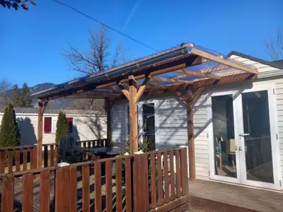 a wooden pergola on a porch of a house at Joli mobil home tout équipé 4 personnes in Samoëns