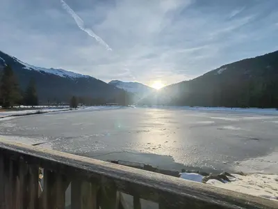 a frozen lake with the sun setting in the mountains at Joli mobil home tout équipé 4 personnes in Samoëns