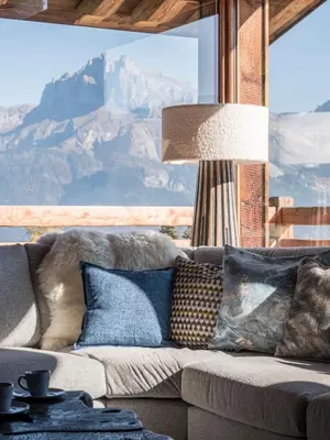 a living room with a couch with pillows and a lamp at Chalet Marianna I Le Chalet Club in Combloux