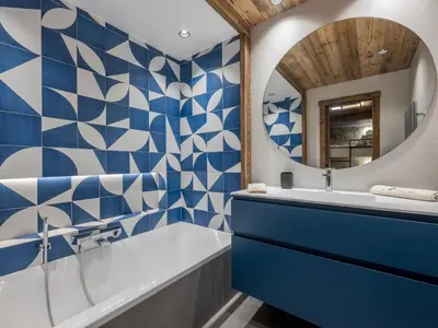 a blue and white bathroom with a tub and a mirror at Chalet Marianna I Le Chalet Club in Combloux