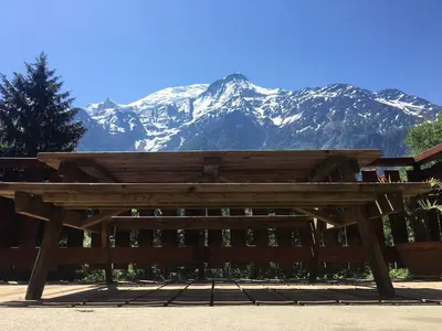 a wooden bench with snow capped mountains in the background at Petite Floria in Les Houches